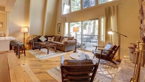 A spacious living room with a high ceiling, a large window, and a cozy seating area with a sofa, chairs, and a coffee table. - Near Skiing & Hiking: Carnelian Bay Cabin (Carnelian Bay)