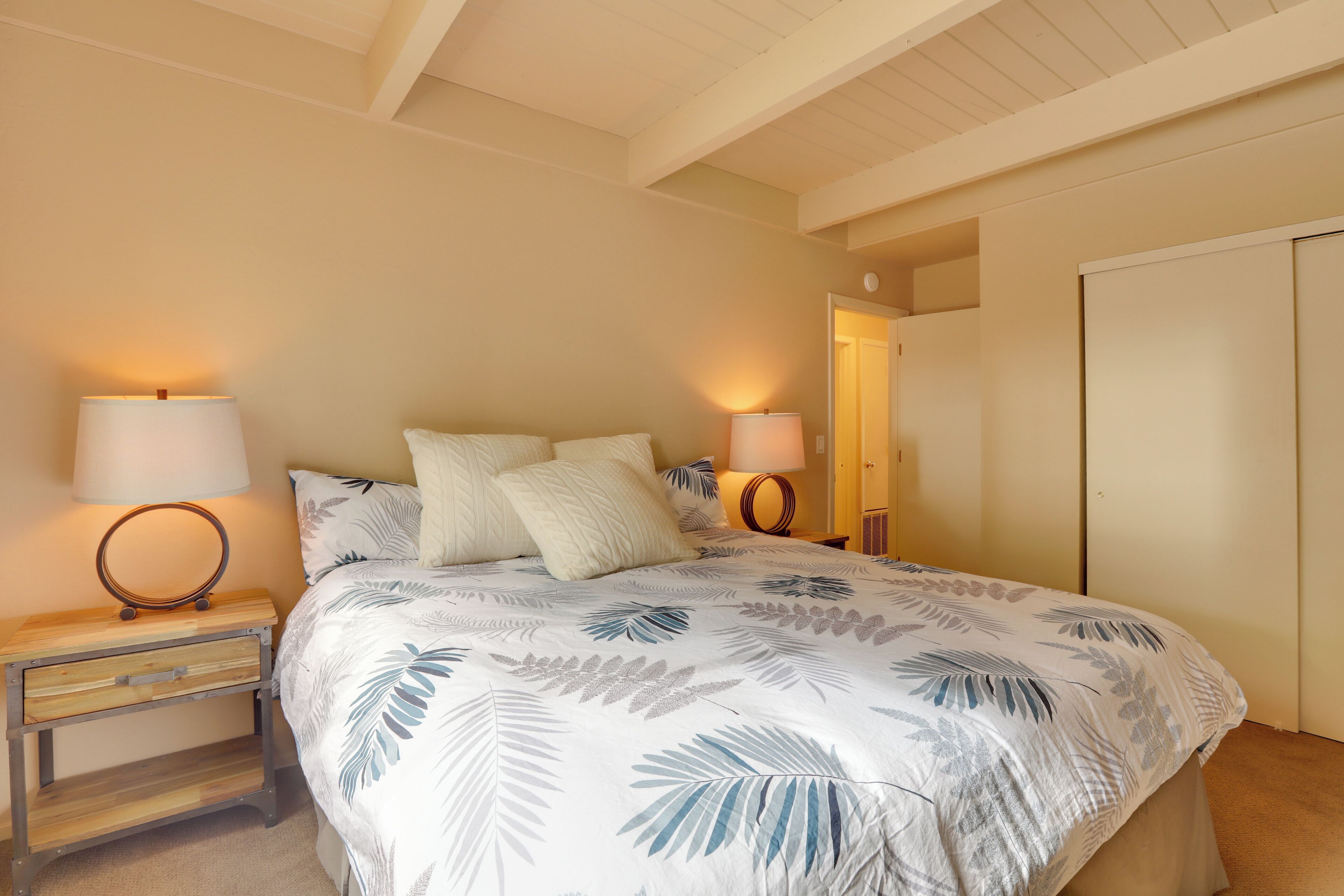 A bedroom with a bed, two bedside tables, lamps, and a wardrobe.