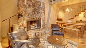 A cozy living room with a stone fireplace, leather chairs, a wooden table, and a staircase. - Near Skiing & Hiking: Carnelian Bay Cabin (Carnelian Bay)