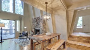A spacious living room with a large wooden table, a fireplace, and a stone accent wall. - Near Skiing & Hiking: Carnelian Bay Cabin (Carnelian Bay)