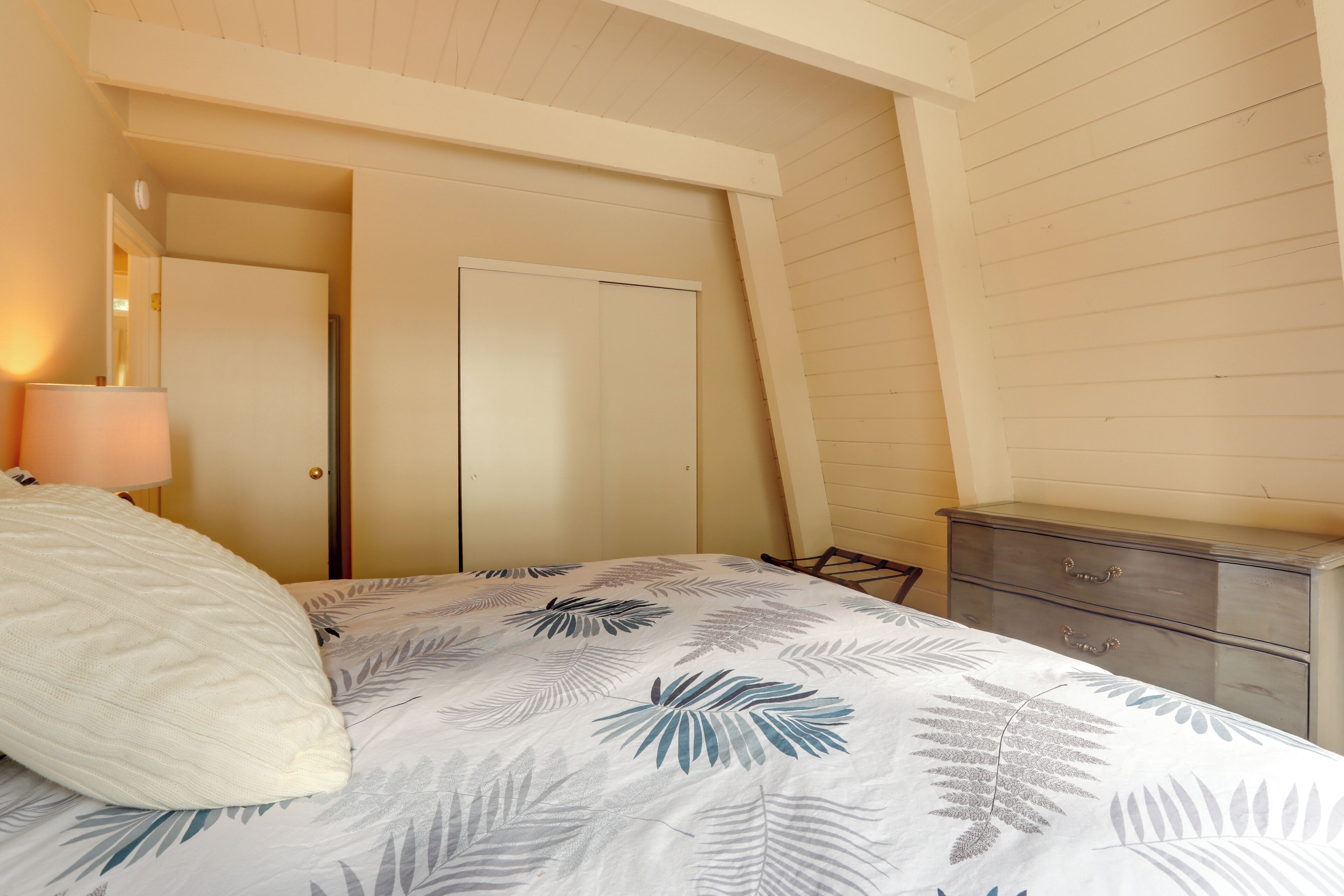 A bedroom with a bed, a nightstand, a dresser, and a door.