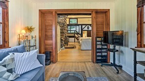 A cozy living room with a sofa, a television, and a bookshelf. - Historic 1800s Cornwall-on-hudson Cottage! (Cornwall)