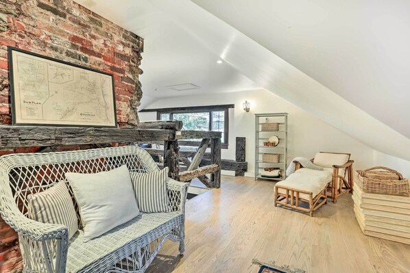A loft-style room with a white wicker sofa, a wooden ladder, and a map on the wall. - Historic 1800s Cornwall-on-hudson Cottage! (Cornwall)