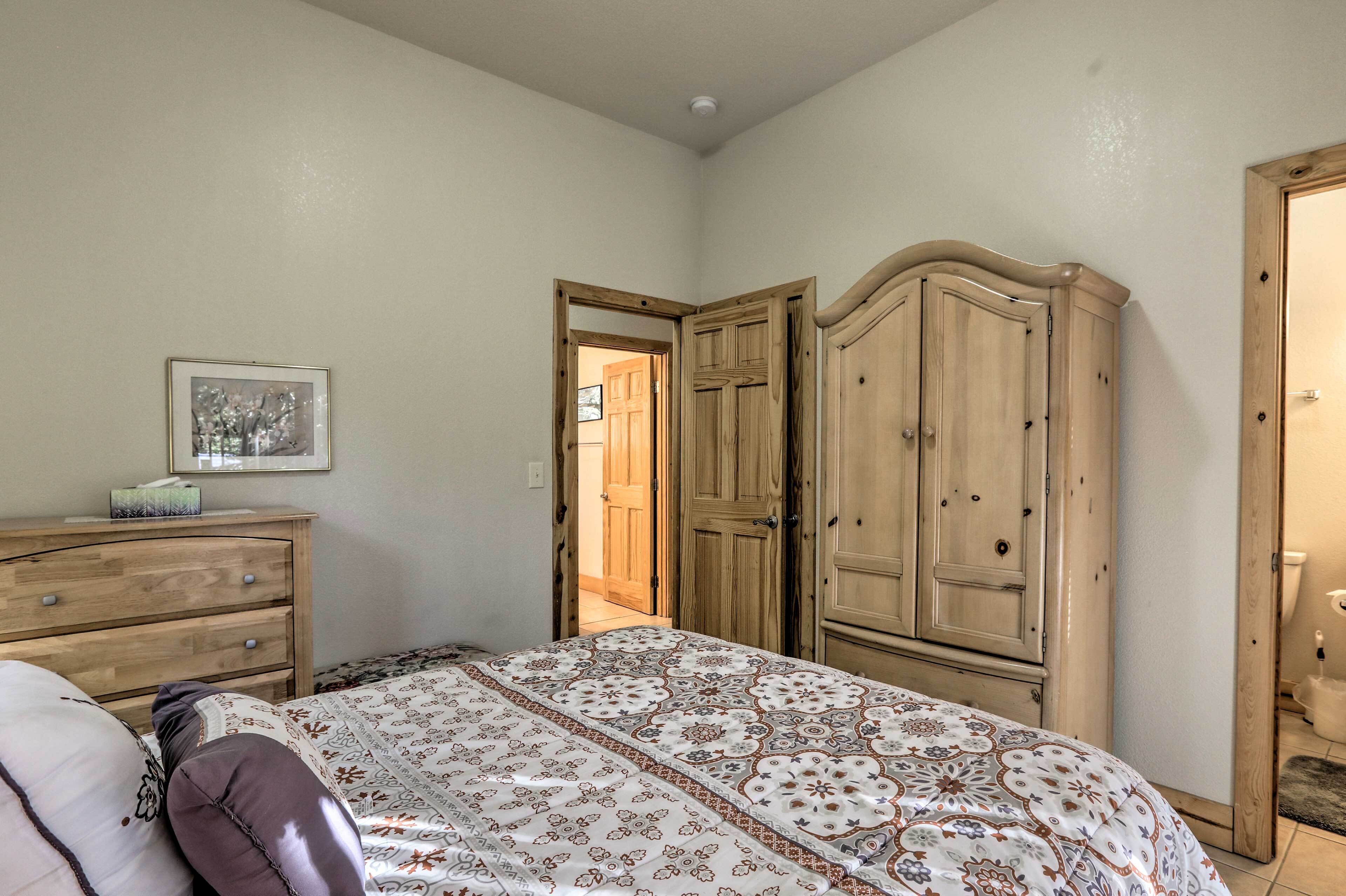 A bedroom with a bed, wooden wardrobe, and a dresser.