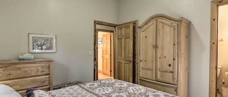 A bedroom with a bed, wooden wardrobe, and a dresser.