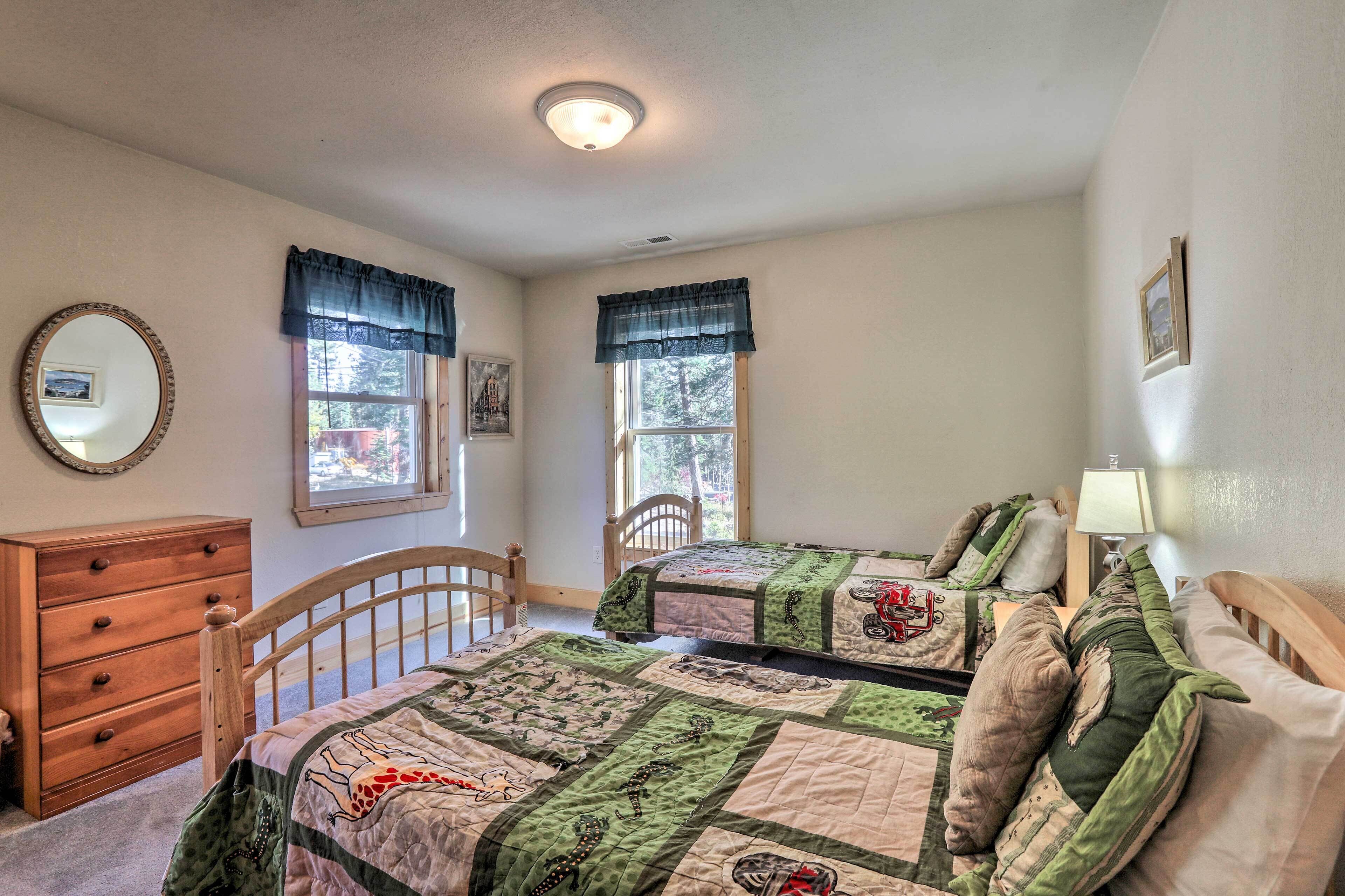A bedroom with two beds, a wooden dresser, and a mirror.