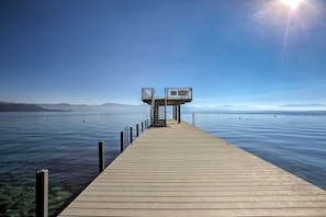 A wooden pier leading to a lifeguard tower on a calm lake with clear water and distant mountains. - Carnelian Bay Home w/ Hot Tub Near Tahoe Skiing (Carnelian Bay)