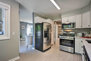 A modern kitchen with stainless steel appliances, white cabinetry, and a light wood floor. - Annapolis Vacation Home: 2 Mi to Quiet Waters Park (Annapolis)