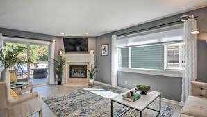Ein großzügiges Wohnzimmer mit Kamin, großen Fenstern und Blick ins Freie.