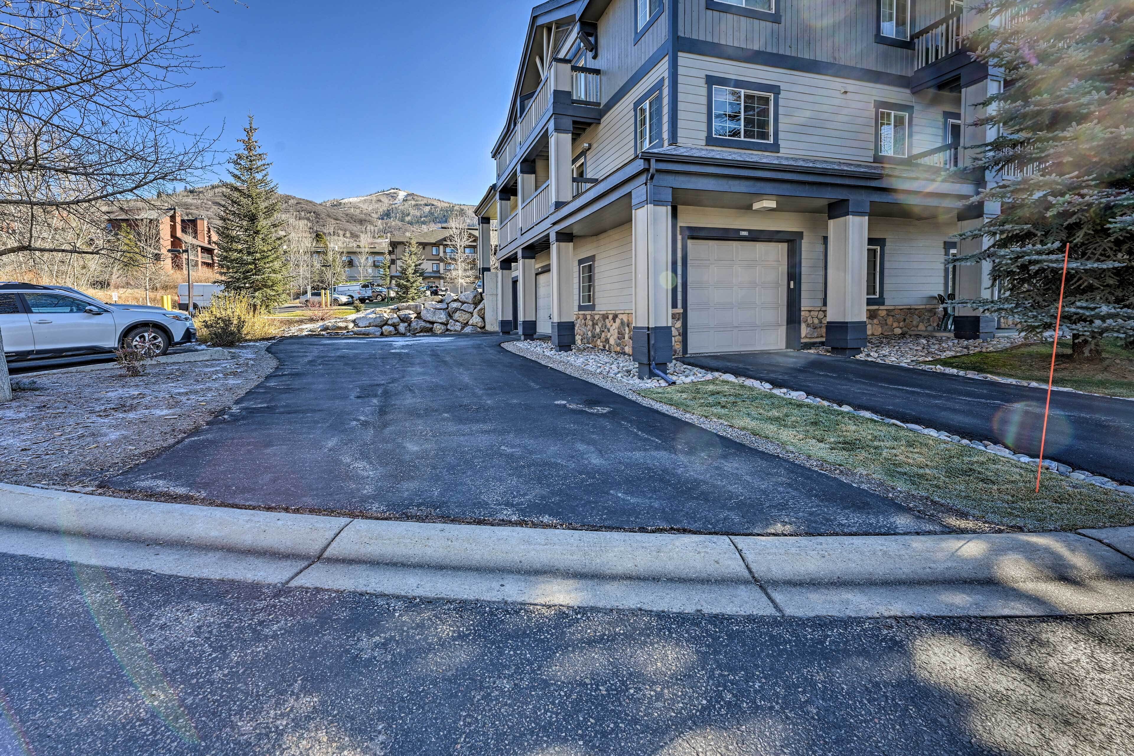 A multi-story residential building with a garage, a driveway, and a parking area.