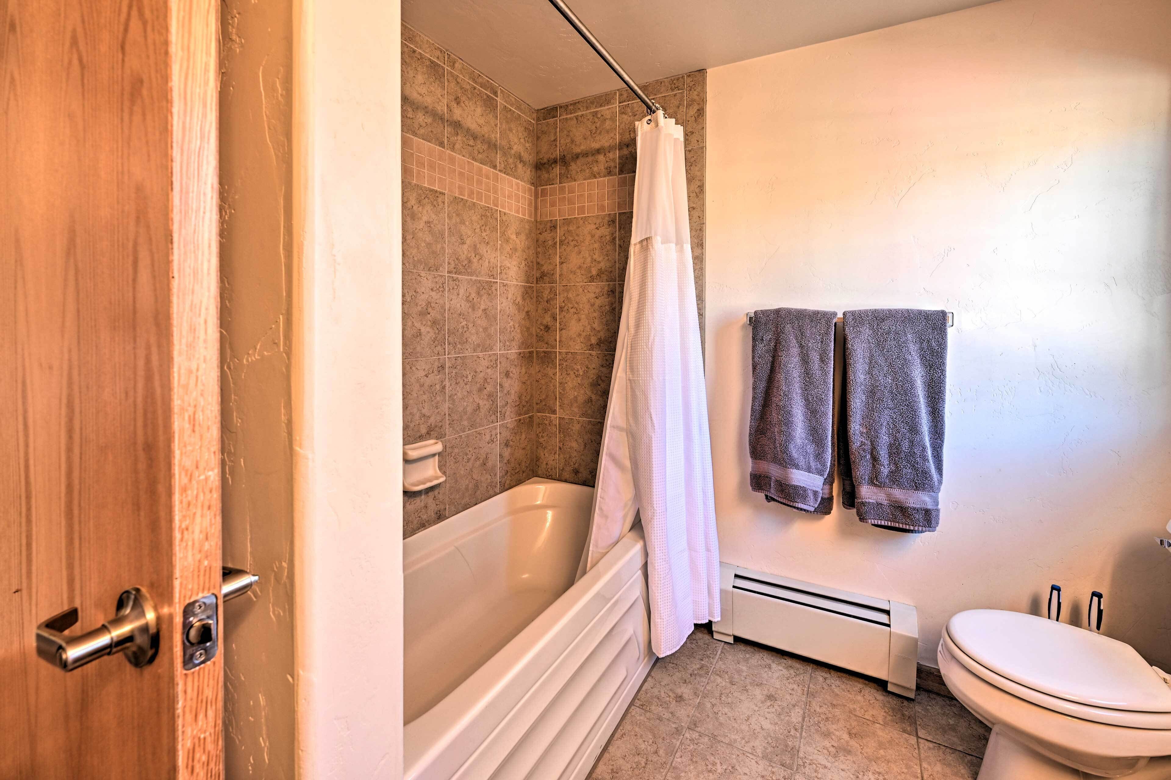 A bathroom with a bathtub, toilet, and towel rack.