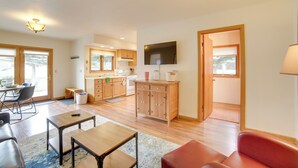 A spacious living area with a dining table, a red sofa, and a kitchen in the background. - Mountain-view Retreat - 6 Mi to Ouray Hot Springs! (Ridgway)