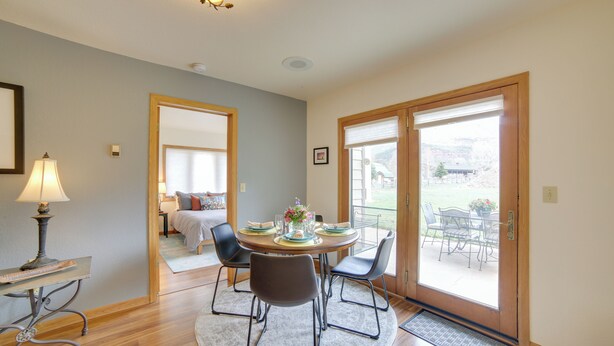 A dining area with a round table, four chairs, a lamp, and a view through a glass door to an outdoor patio. - Mountain-view Retreat - 6 Mi to Ouray Hot Springs! (Ridgway)