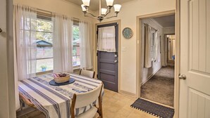 A dining area with a table set for two, a chandelier, and a view of the outside. - Ranch-style Cottage - 2 Miles to Philbrook Museum! (Tulsa)