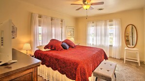 A bedroom with a bed, a desk, a chair, a ceiling fan, and a mirror. - Ranch-style Cottage - 2 Miles to Philbrook Museum! (Tulsa)