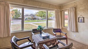 A room with a large window, a table with chairs, and a vase with flowers. - Ranch-style Cottage - 2 Miles to Philbrook Museum! (Tulsa)