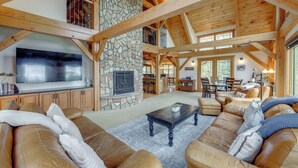 A spacious living area with a stone fireplace, wooden beams, a large TV, leather sofas, and a dining area in the background. - 7 Mi to Rocky Mtn Nat'l Park: Grand Lake Home! (Grand Lake)