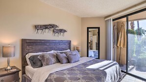 Une chambre avec un grand lit, deux lampes de chevet, une tête de lit en bois foncé et une vue sur l’extérieur grâce à une porte-fenêtre coulissante.
