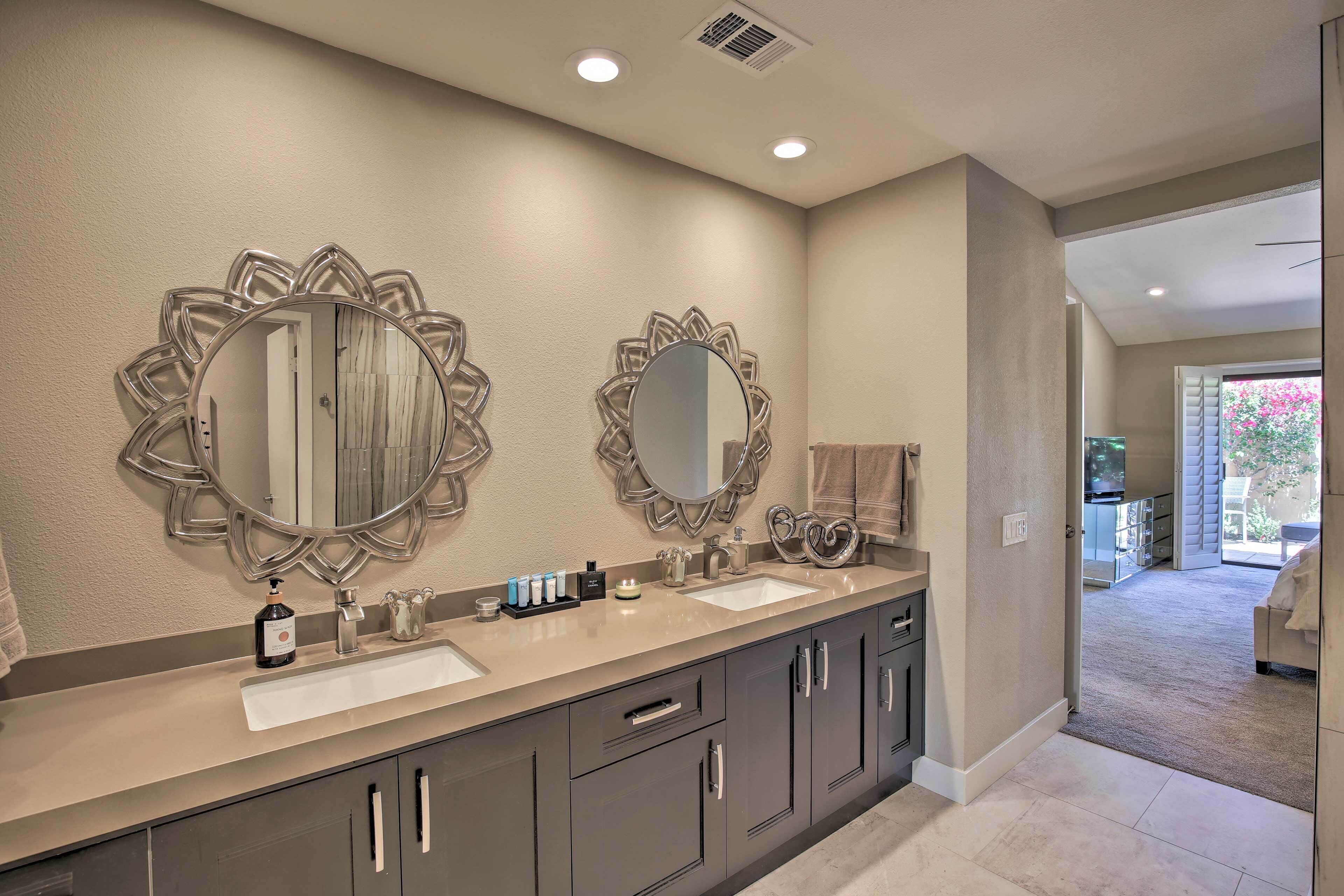 A bathroom with two large mirrors, a double sink vanity, and a walk-in closet.