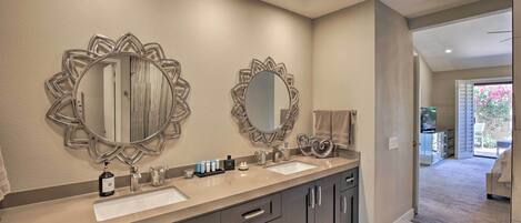A bathroom with two large mirrors, a double sink vanity, and a walk-in closet.
