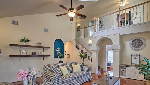 A spacious living room with a checkered sofa, a coffee table, and a staircase leading to an upper level. - San Antonio Home w/ Pool & Hot Tub Near Seaworld! (San Antonio)