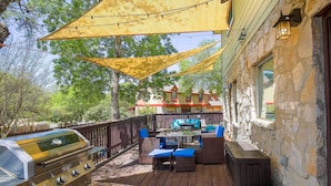 A deck with a grill, outdoor furniture, and a stone building in the background. - San Antonio Home w/ Pool & Hot Tub Near Seaworld! (San Antonio)