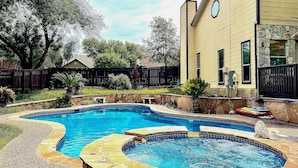 A backyard with a swimming pool, stone patio, and a house with a stone facade. - San Antonio Home w/ Pool & Hot Tub Near Seaworld! (San Antonio)