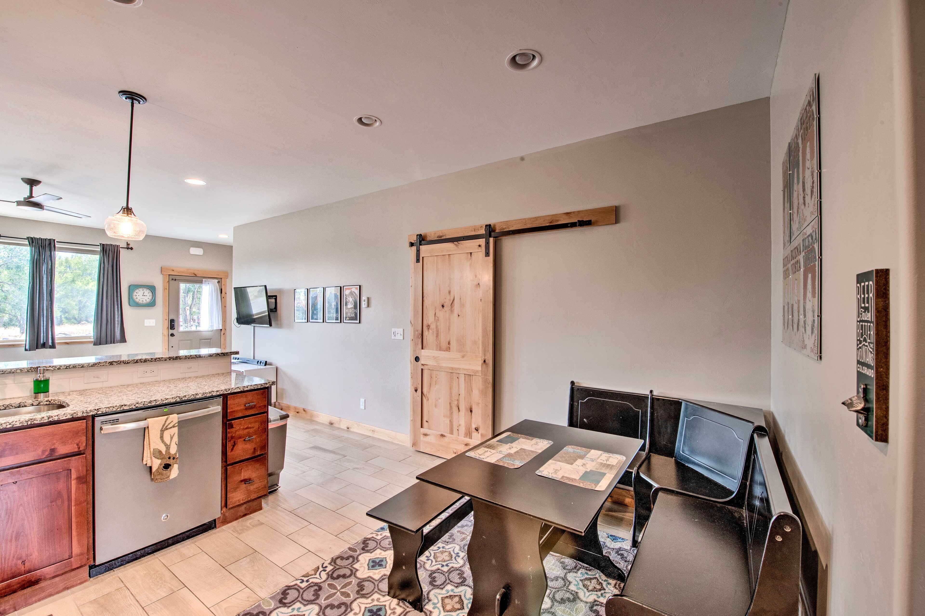 A modern kitchen with a large island, a dining area with a table and chairs, and a sliding barn-style door.