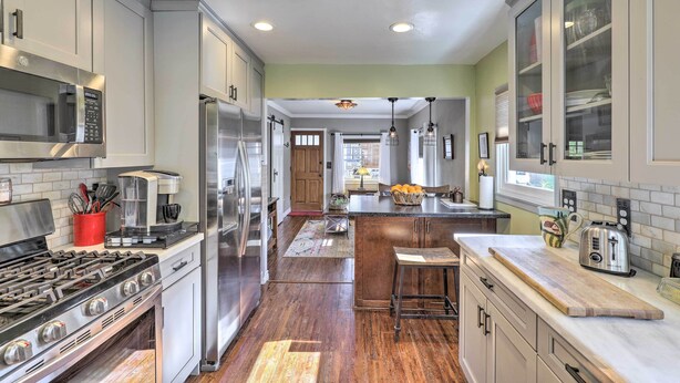 A modern kitchen with stainless steel appliances, a central island, and a view to the dining area. - Charming Craftsman Bungalow With Garden & Hot Tub! (Fullerton)
