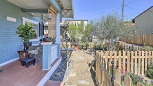 A covered porch with outdoor furniture, a small garden area with plants and a wooden fence. - Charming Craftsman Bungalow With Garden & Hot Tub! (Fullerton)