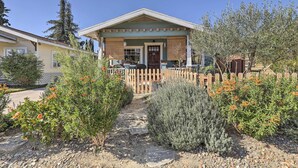 A two-story building with a porch, a wooden fence, and a gravel pathway. - Charming Craftsman Bungalow With Garden & Hot Tub! (Fullerton)