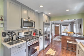 A modern kitchen with stainless steel appliances, a gas stove, and a large island with a sink. - Charming Craftsman Bungalow With Garden & Hot Tub! (Fullerton)