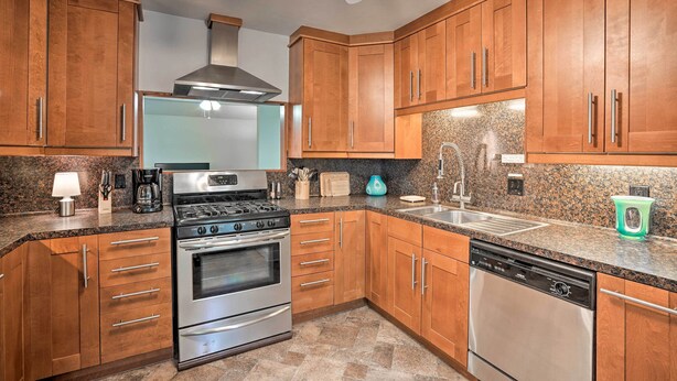 A kitchen with wooden cabinets, stainless steel appliances, granite countertops, and a ceiling fan. - San Antonio Home w/ Pvt. Yard, 5 Mi to Downtown! (San Antonio)