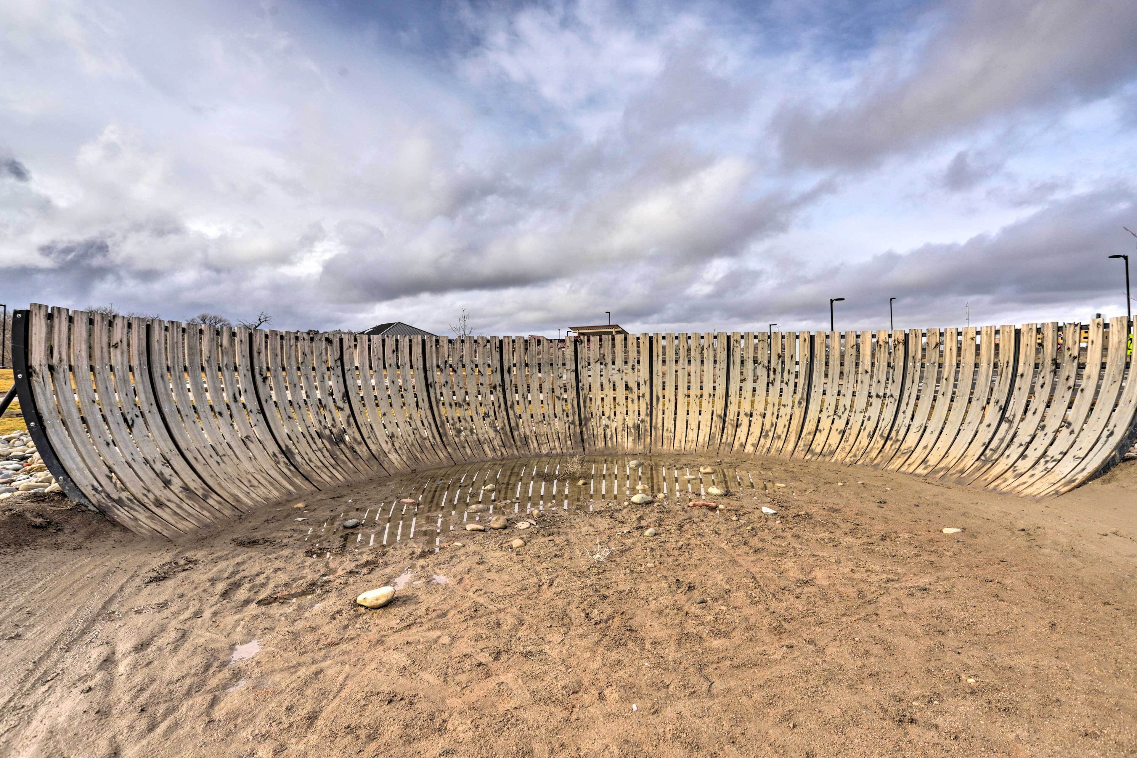 Une vaste structure incurvée en béton, avec un sol sablonneux devant.