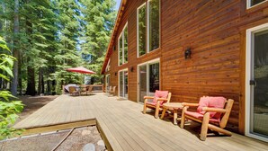 Una terraza de madera con una mesa y sillas, rodeada de un bosque.
