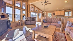 A spacious living area with large windows, a wooden ceiling, and a fireplace.