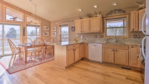 A spacious kitchen with wooden cabinets, a granite countertop, and a dining area with wooden chairs.