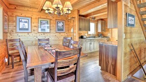 A wooden interior with a dining table, chairs, a chandelier, framed pictures on the wall, and a kitchen area. - 1 Mi to Granby Ranch: Family-friendly Cabin! (Granby)