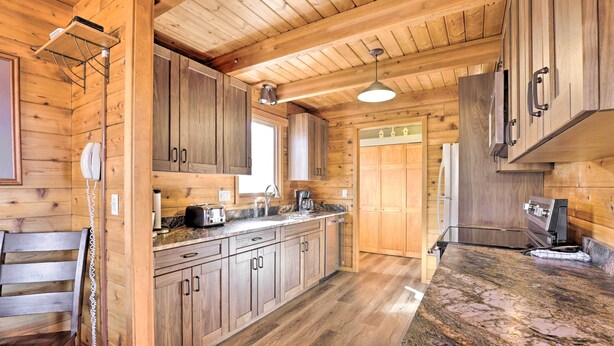 A wooden cabin-style kitchen with a granite countertop, wooden cabinets, and a built-in stove. - 1 Mi to Granby Ranch: Family-friendly Cabin! (Granby)