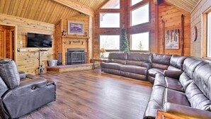 A spacious living room with a fireplace, leather sofas, and a television mounted on the wall. - 1 Mi to Granby Ranch: Family-friendly Cabin! (Granby)
