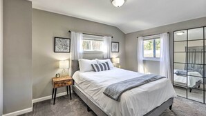 A bedroom with a large bed, bedside tables, a mirror, and a window with curtains. - Chic Townhome w/ Deck: 6 Mi to Dtwn Baltimore (Baltimore)