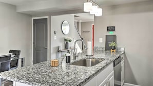 A modern kitchen with granite countertops, stainless steel appliances, and a hanging light fixture. - Chic Townhome w/ Deck: 6 Mi to Dtwn Baltimore (Baltimore)