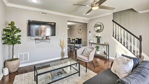 A modern living room with a flat-screen TV, a ceiling fan, a staircase, and a dining area in the background. - Chic Townhome w/ Deck: 6 Mi to Dtwn Baltimore (Baltimore)