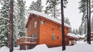 Eine Holzhütte mit Balkon, umgeben von schneebedeckten Bäumen.