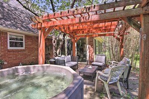 Un patio cubierto con un jacuzzi, mobiliario exterior y una pérgola de madera.