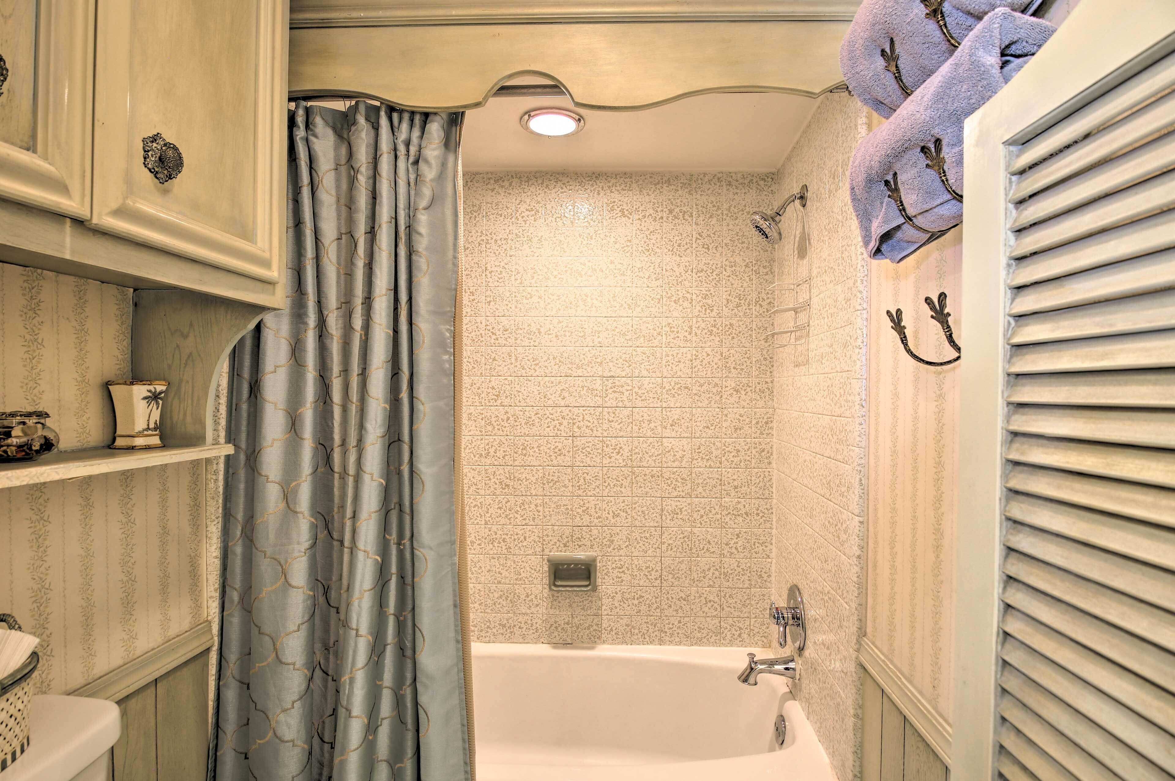 A bathroom with a bathtub, shower, and a towel rack with towels.