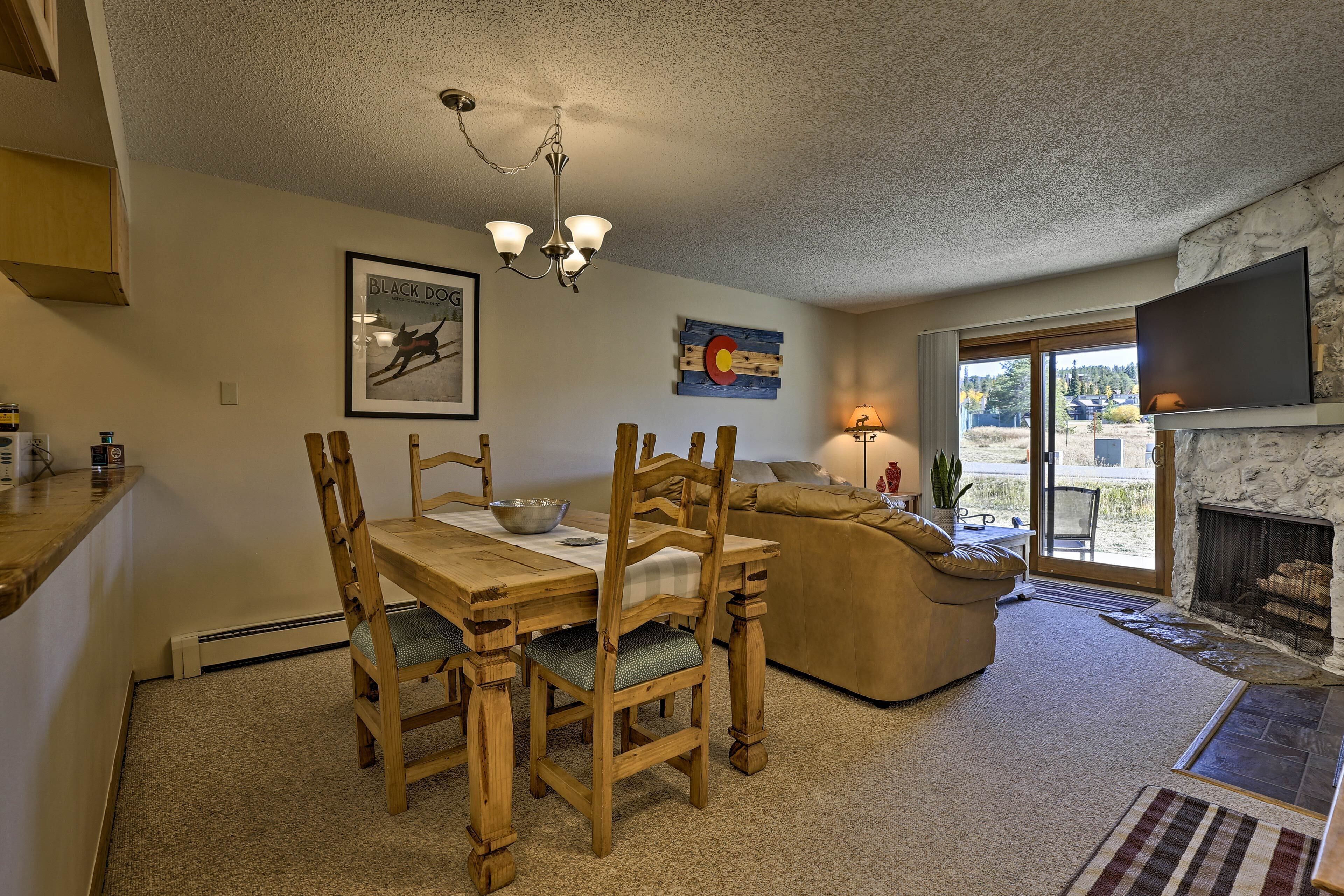 A dining area with a wooden table and chairs, a chandelier, a painting, and a sofa.