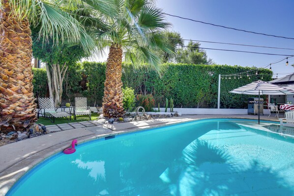 A swimming pool with palm trees, a hedge, and outdoor furniture. - 5 Blocks to El Paseo: Palm Desert Casita w/ Pool (Palm Desert)
