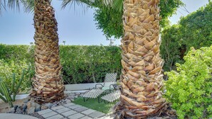 Ein Garten mit Palmen, einem Steinweg und Gartenmöbeln.