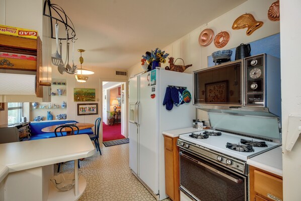 Una cocina con estufa, refrigerador y sillas azules alrededor de una mesa.